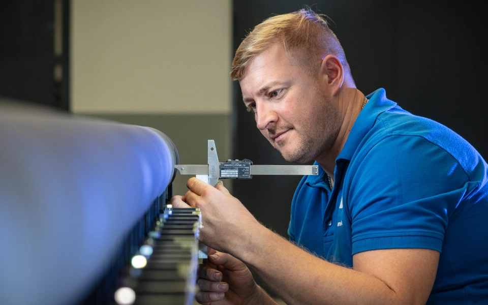 Mitarbeiter in der Maschinenbauwerkstatt bei der Qualitätsprüfung eines Werkstücks, um Toleranzen und Anforderungen zu überprüfen.