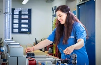 Teilnehmerin der Umschulung zur Industrieelektrikerin für Betriebstechnik führt Messungen und Spannungsprüfungen an elektrischen Anlagen in der Elektroausbildungswerkstatt durch.