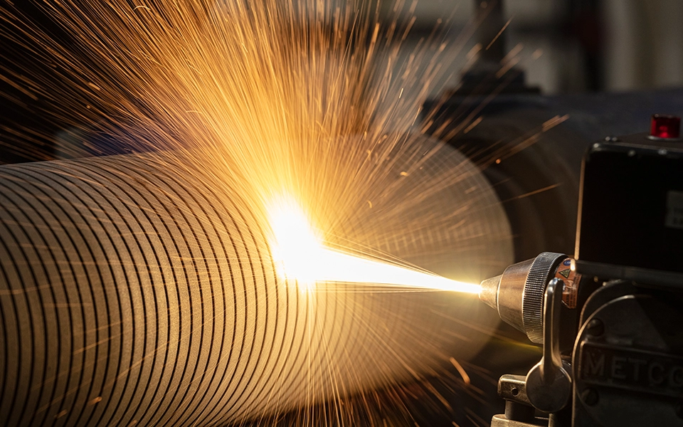 Detailaufnahme der Flamme einer Flammspritzanlage, die im Maschinenbau zur Materialbeschichtung eingesetzt wird.