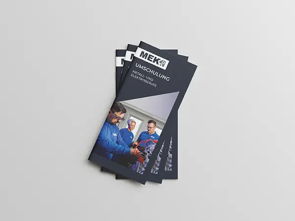 Stapel von drei gefächerten DIN Lang Flyern zur Umschulung auf grauem Hintergrund.