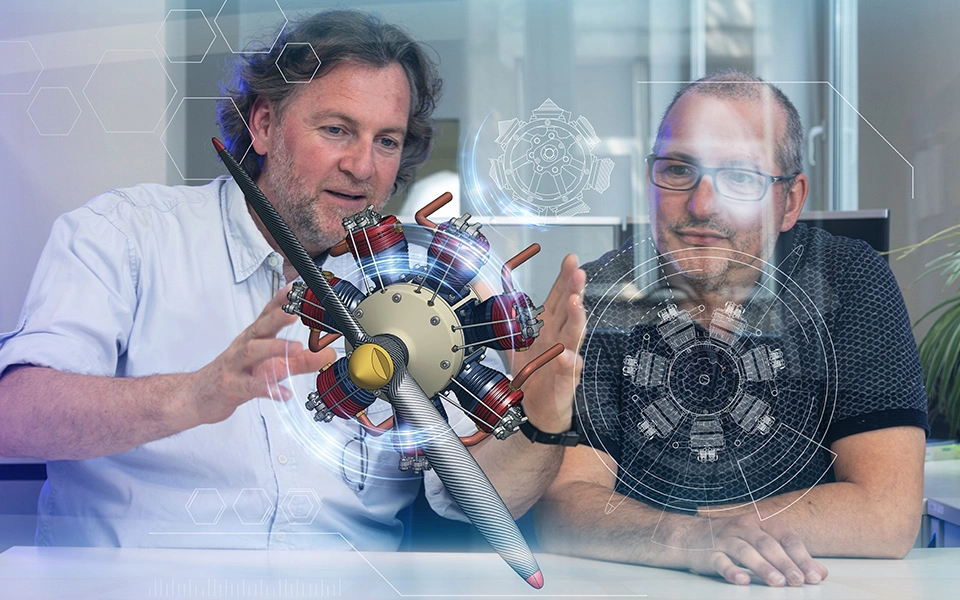 Ausbildungssituation während der Umschulung zum Technischen Produktdesigner: Ausbilder und Teilnehmer betrachten eine 3D-Zeichnung eines Körpers im Raum.