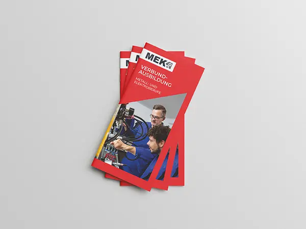 Stapel von drei gefächerten DIN Lang Flyern zur Verbundausbildung auf grauem Hintergrund.