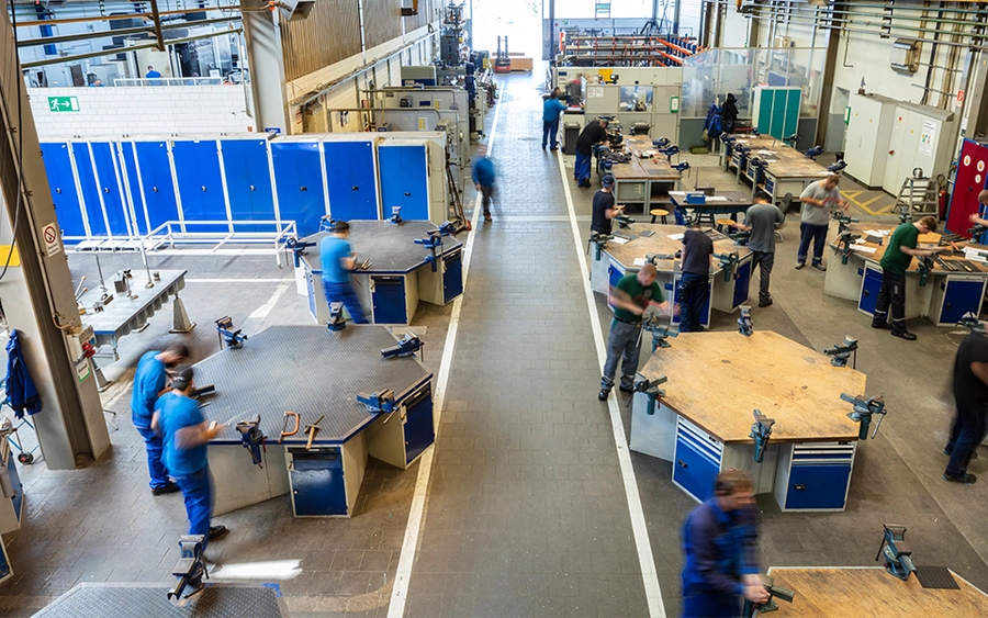 Vogelperspektive der Metallgrundausbildung in Krefeld, mit Teilnehmern, die an Werkstücken und Maschinen arbeiten.
