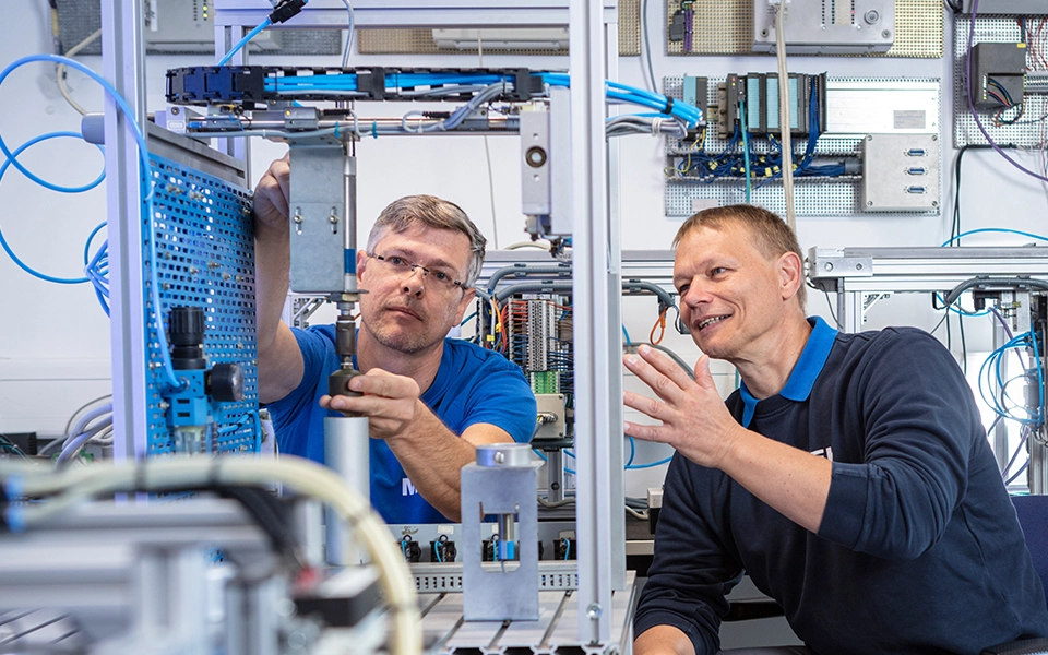 Ausbilder erklärt einem Teilnehmer die Anwendung von SPSS in einer Ausbildungssituation.